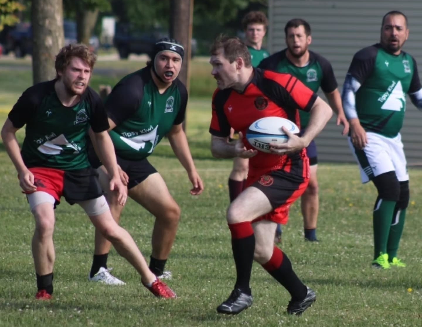 Escanaba Berserkers ball carrier in red and black running as defenders close in